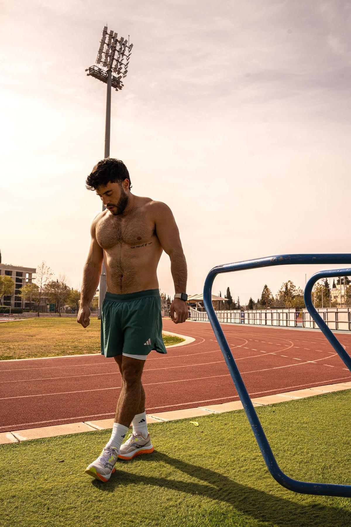 גד פנש - מאמן כוח וריצה, הולך ליד מסלול ריצה בשקיעה